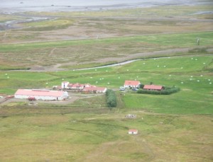 Mynd tekin í hlíðinni ofan við bæinn og horft yfir Mosvallaskeið.
Fyrir neðan eru svo eldri útihús. Litla húsið fyrir ofan bæjarstæðið hýsir vélbúnað virkjunar sem lengi hefur þjónað bændunum á vöðlum.
